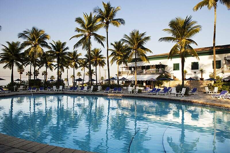 Grande piscina central em meio coqueirais